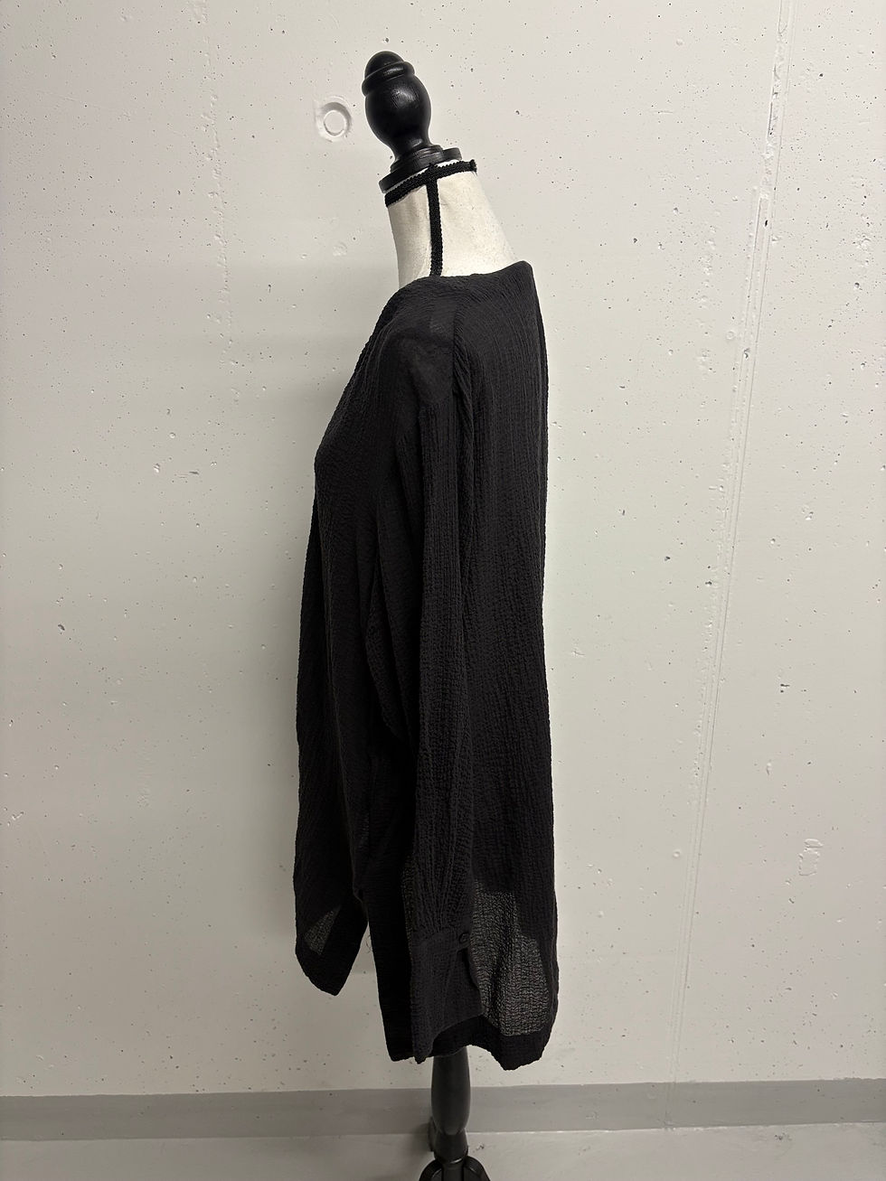 Schwarzes Hemd auf einer Schaufensterpuppe. Modekleidung, Seitenansicht, Detailaufnahme.