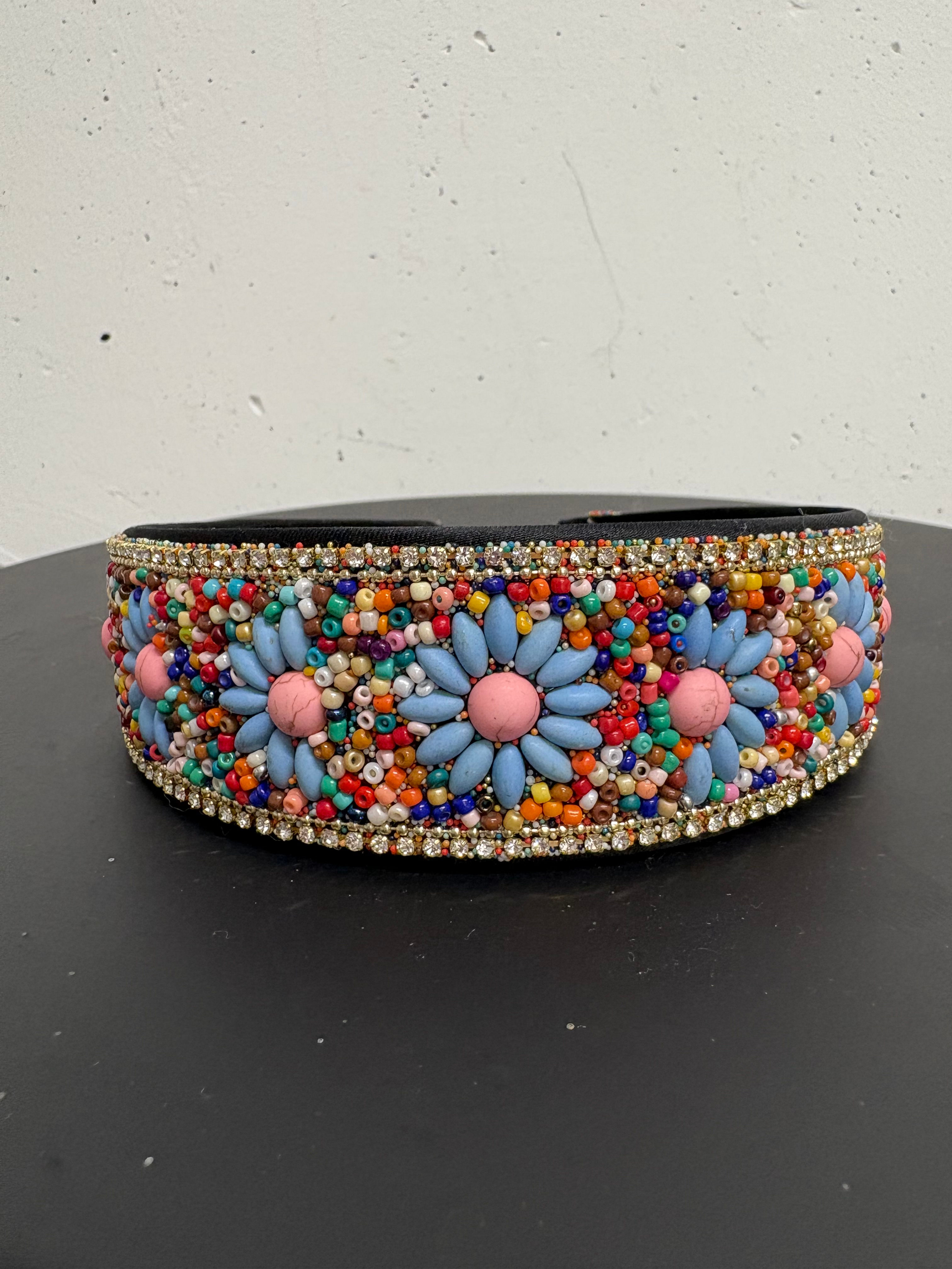 Haarreif mit blauen Blumen und bunten Perlen auf schwarzem Untergrund.