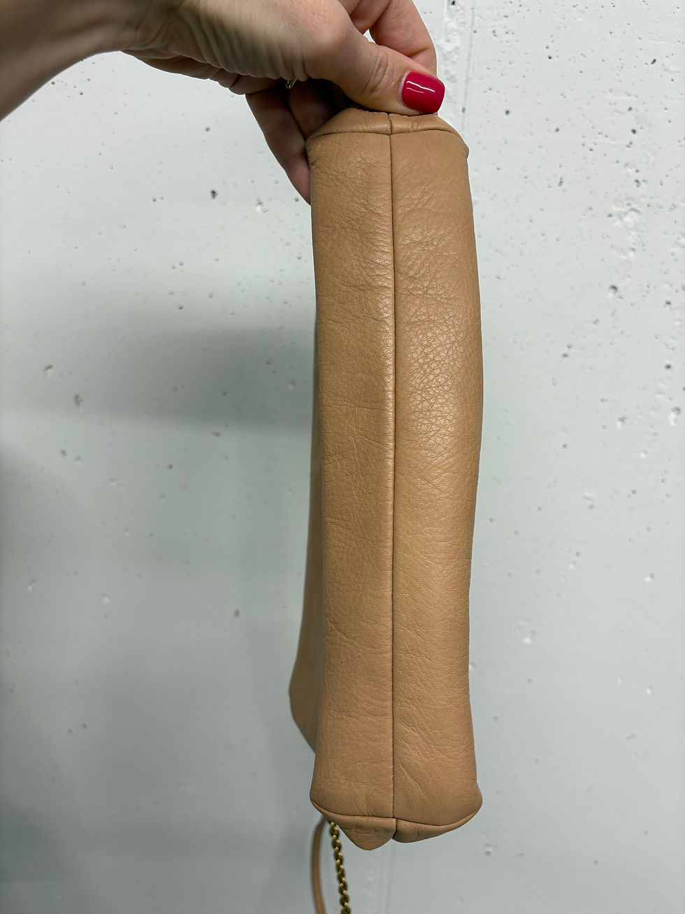 Miniaturbild: Beigefarbene Lederhandtasche, vertikal gehalten, mit sichtbarer Naht und glattem Hintergrund.