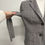 Miniaturbild: Person's hand adjusting a gray checked blazer with buttons and white background.