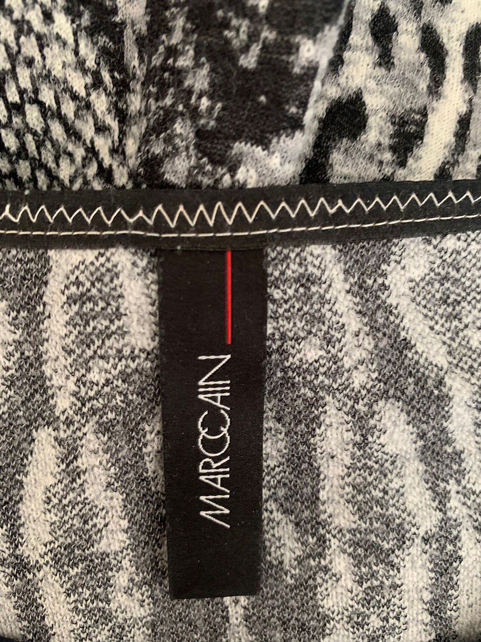 Miniaturbild: Nahaufnahme des MARCCAIN-Etiketts auf einem Kleidungsstück mit Schlangenmuster. Detailansicht.
