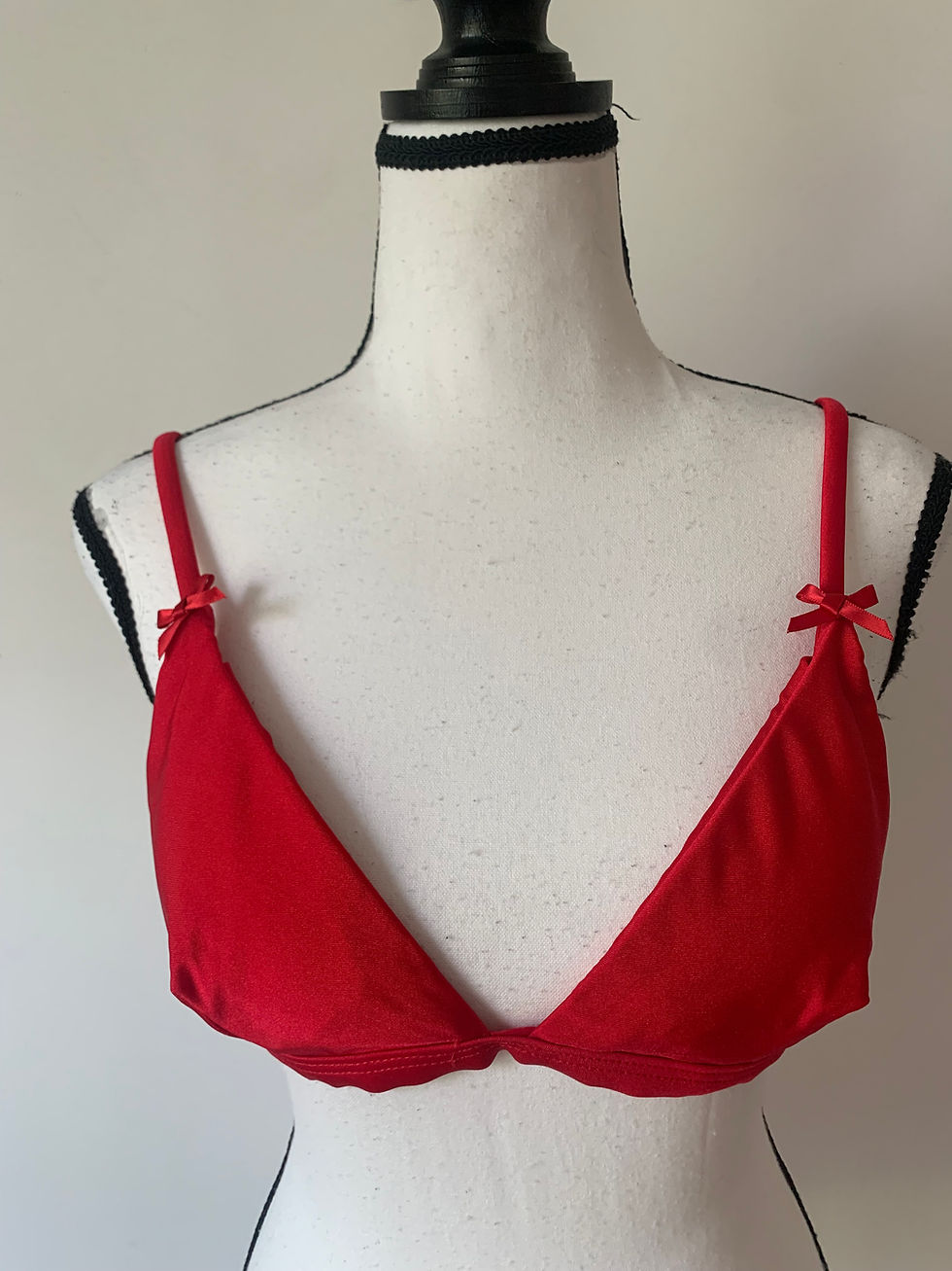 Roter BH, mit feinen Schleifen verziert, auf einer Schaufensterpuppe präsentiert.