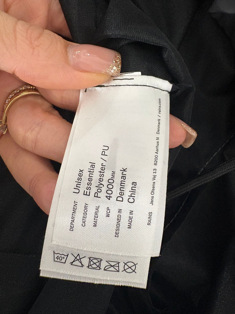 Miniaturbild: White clothing tag with text: Unisex Essential Polyester / Pu, Made in Denmark.