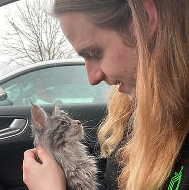 Man with long hair holding a Maine Coon kitten