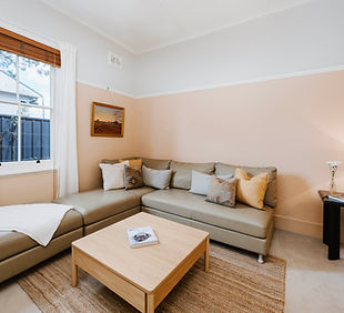 A living room with a modular sofa with chaise, neutral colours, cushions and a coffee table.