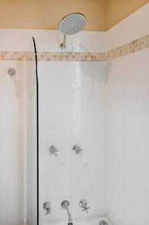 Shower head and controls in a white tiled bathroom setting.
