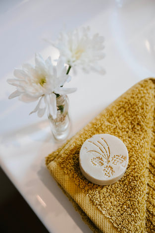 White flowers beside a bar of custom made Bilawi soap on a thick cotton face washer.