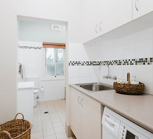 Laundry room with sink, cabinets, and a washing machine.