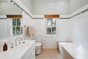 Modern white bathroom with window, toilet, sink, and bathtub; thick cotton towels.