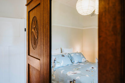 Bedroom view through Art Nouveau style wooden door with bedding and paper lamp hanging