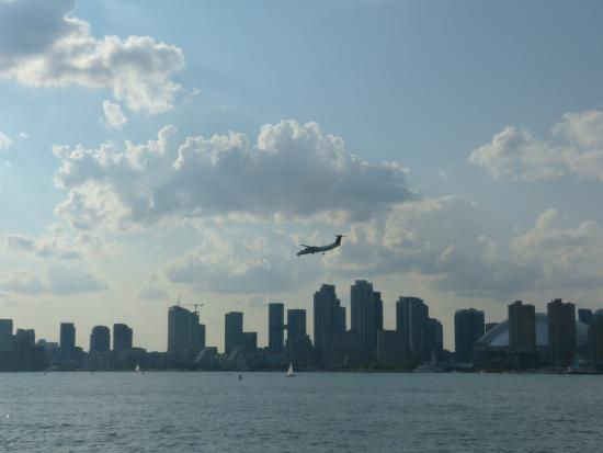 An airplane flying above the Toronto, Canada skyline on a summer day.