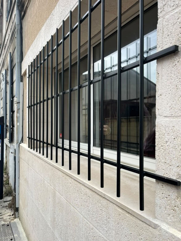 Grille de protection noire à barreaux verticaux sur baie vitrée