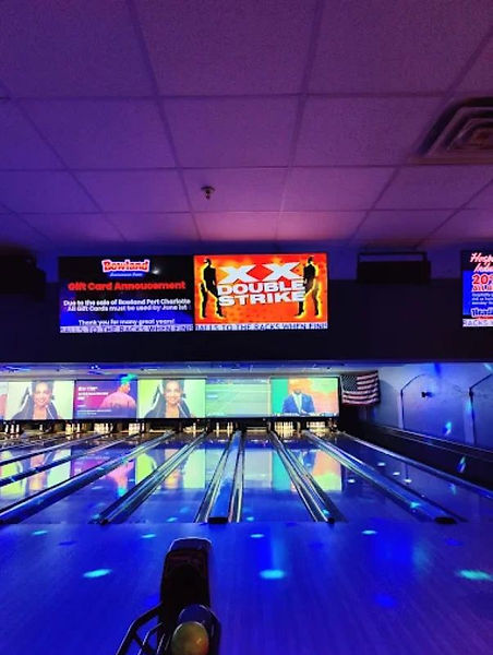 Bowling lanes with colorful blue and purple lighting inside Bowl 360 Port Charlotte.