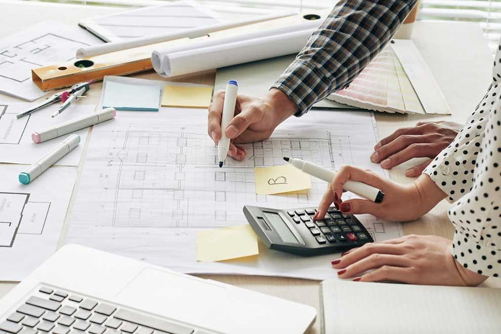 Construction estimator reviewing plans and quantity takeoffs at a desk