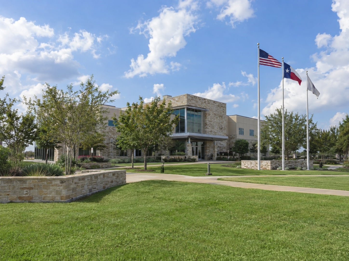 Manvel civic building with landscaped grounds and Texas flags.