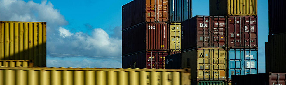 Stacks of colorful shipping containers under a blue sky with clouds. Prominent colors: yellow, red, and blue. Text includes "tex" and "sc".