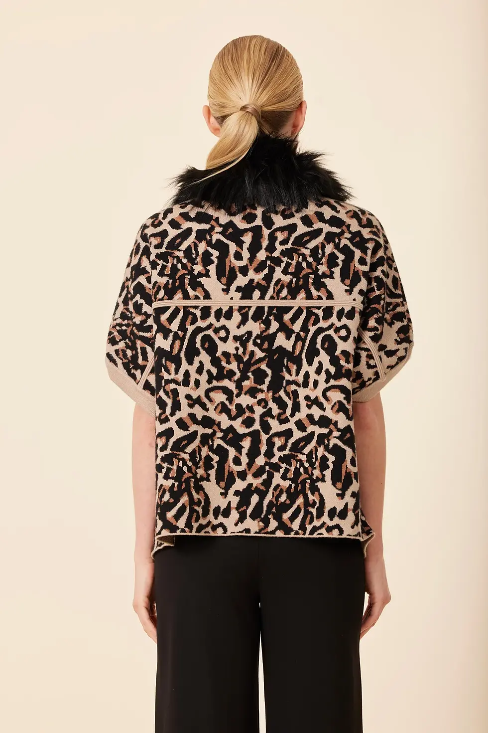 Thumbnail: Back view of a model wearing a black short-sleeve cardigan with a leopard faux-fur collar, arms bare.