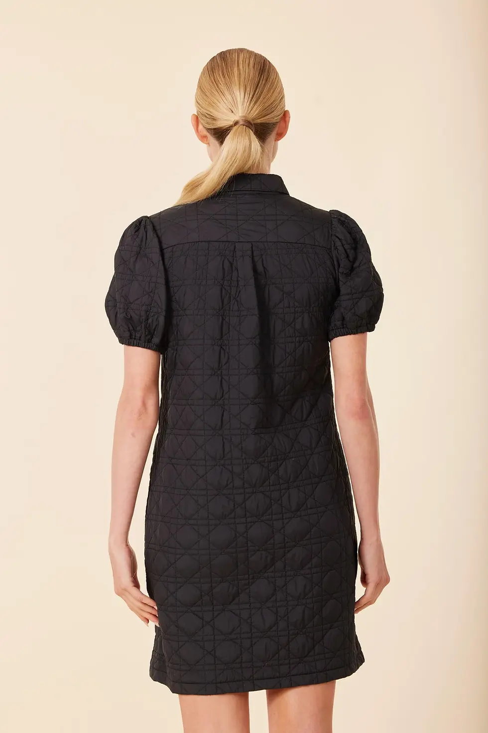 Thumbnail: Nylon quilted short sleeve dress in black  being worn showing the back.