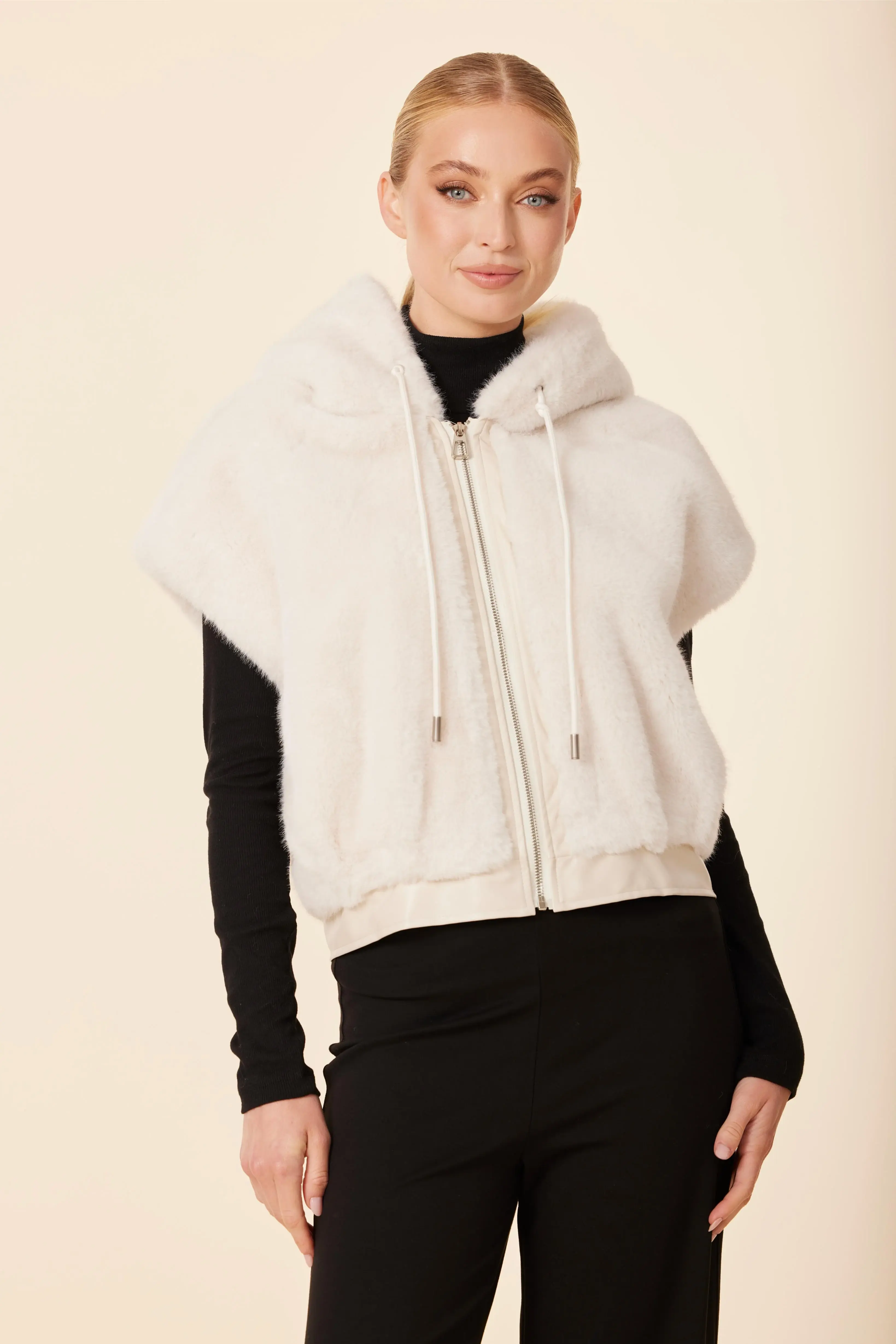 Faux Fur Vegan Leather Trim Hoody Vest Faux in cream being worn over a long black shirt.