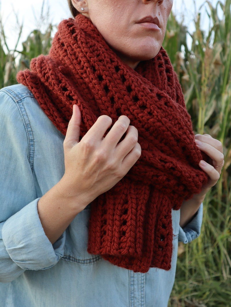 pinterest pin of a girl draped in a handmade copper colored crochet shawl featuring undulating details of ribbing, lace, and bobble stitches
