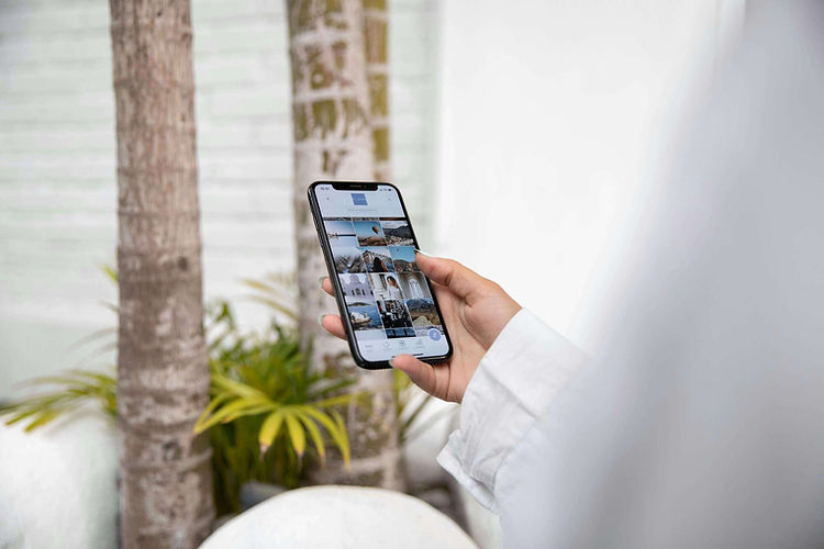 A hand holding a phone looking at a gallery of pictures.