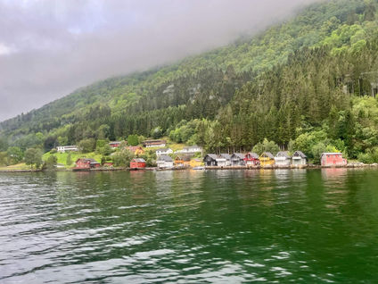 Toddler looking out the large panoramic window of a Norled express ferry at the steep green cliffs of the Sognefjord.
