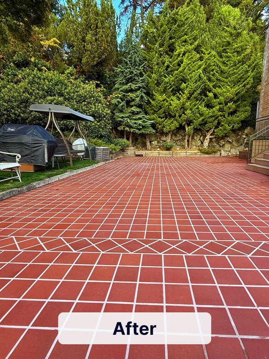Completed outdoor patio renovation with red tile surface and decorative border pattern