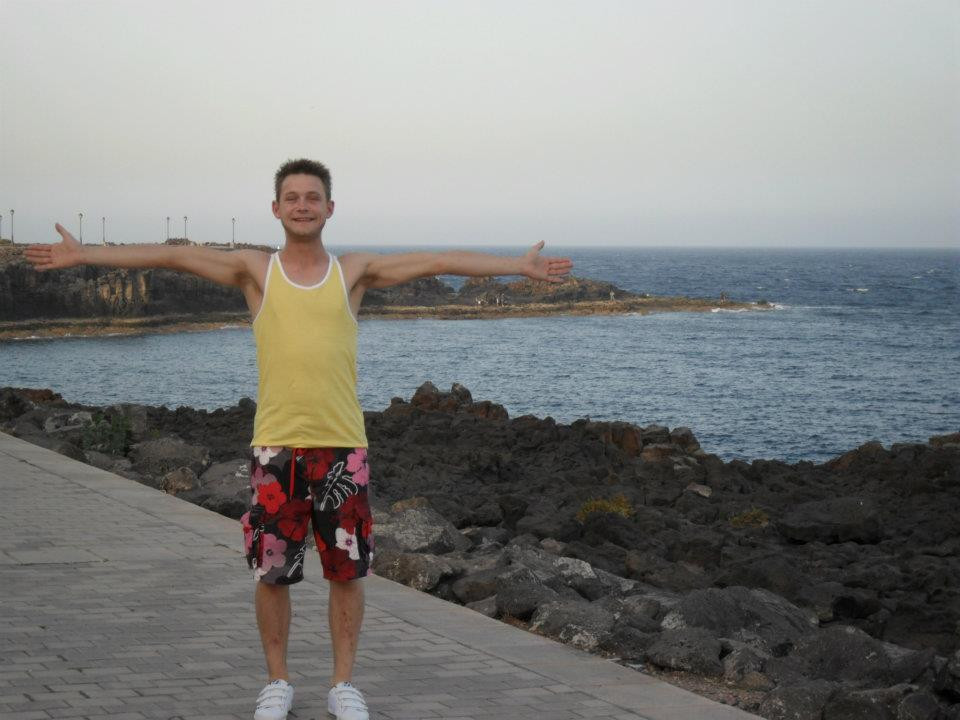 A man by the sea, with arms wide open and a great big smile
