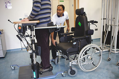 A physiotherapy assists a patient to stand from a wheelchair