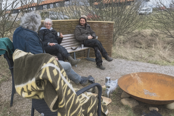 Gruppe mennesker omkring et bålsted udendørs