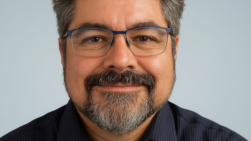 Smiling man with glasses and gray hair, wearing a navy striped shirt, against a light gray background. Relaxed and approachable mood.