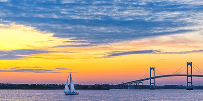 Dramatic yellow orange pink and purple sunset with Claiborne Pell Newport Bridge sailboat