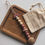 Thumbnail: Speenkoord met rouge halve daisy en ronde houten letterkralen, op een donker houten plaatje met een gepersonaliseerd tasje