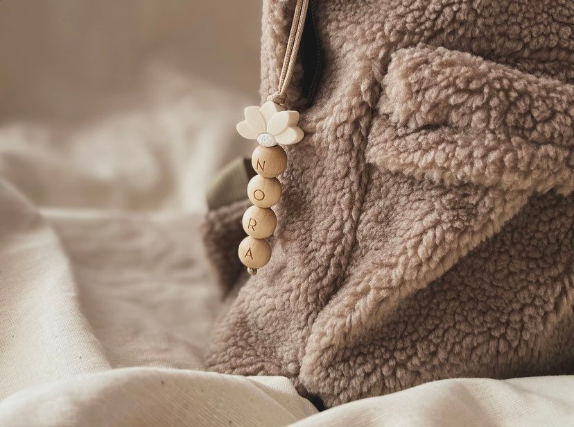 Thumbnail: Tassenhanger met ivory halve daisy en naam met ronde houten letterkralen aan een tas