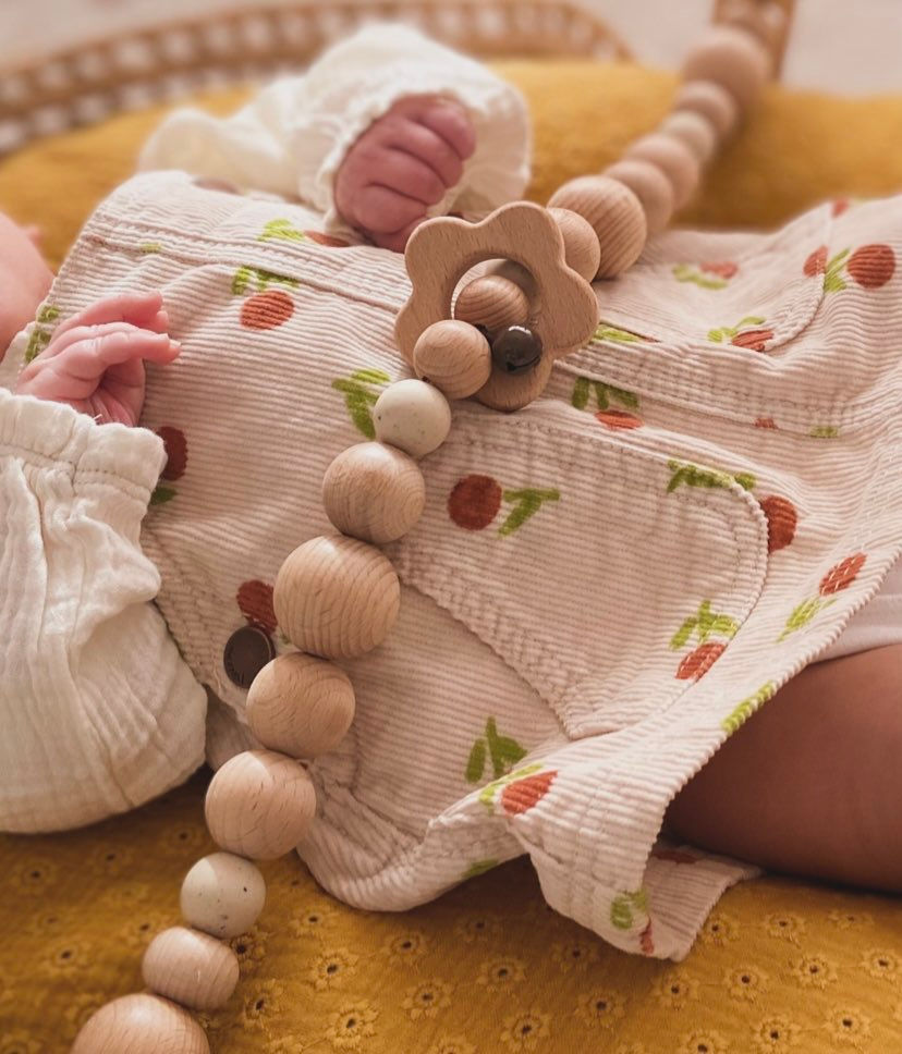 Ivory spikkel wagenspanner en houten bloemenring samen met een baby.