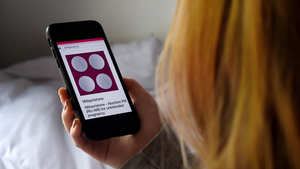 woman holding phone with article about mifepristone on the screen