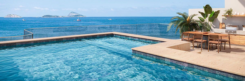 Piscina e área externa do projeto Tom Delfim Moreira, no Leblon (RJ), com deck em pedra natural e vista para o oceano