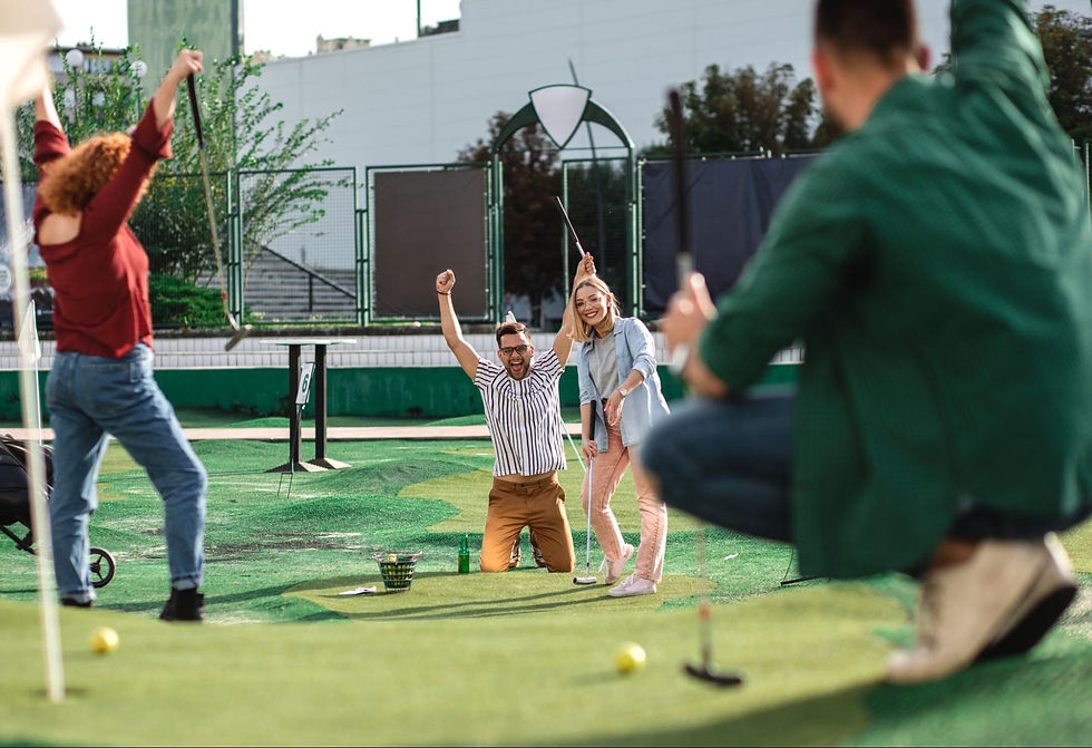 A group of adults playing a mini golf game in a grassy outdoors.