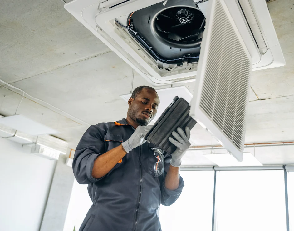 A male service worker is working on an air conditioner unit.