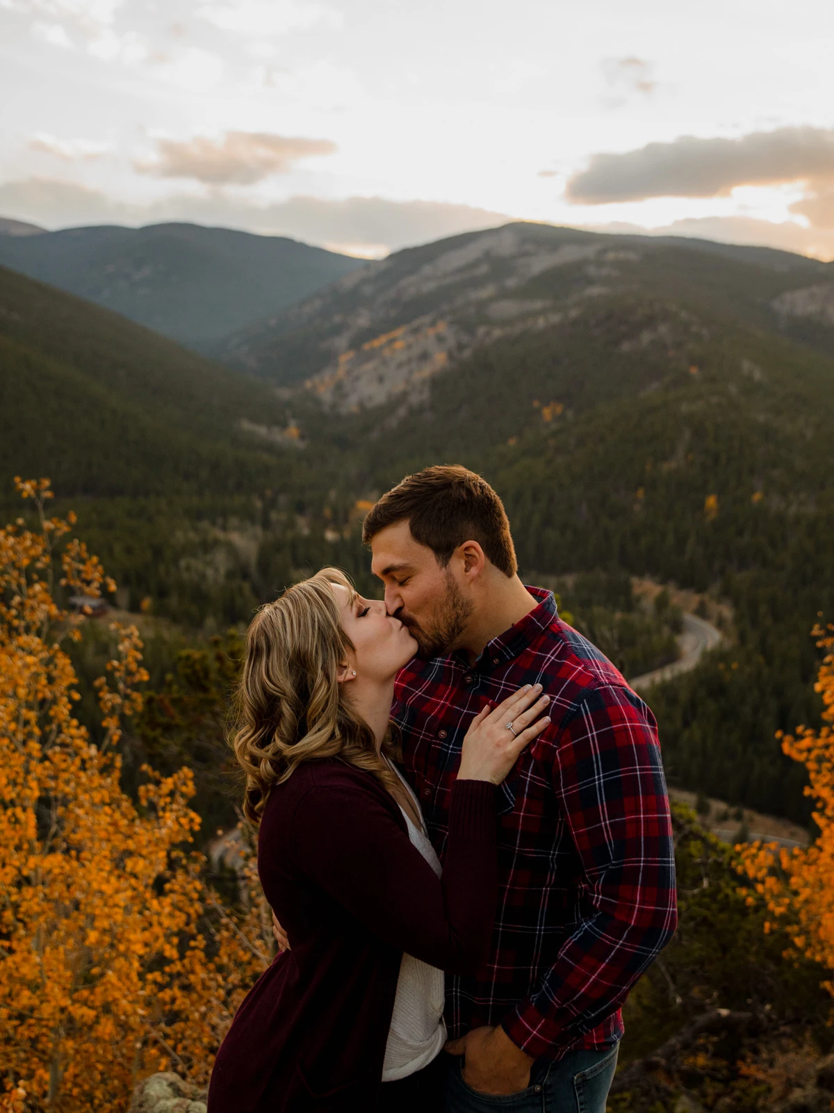 couple kissing with Colorado mountain views in the background during their engagement photo session