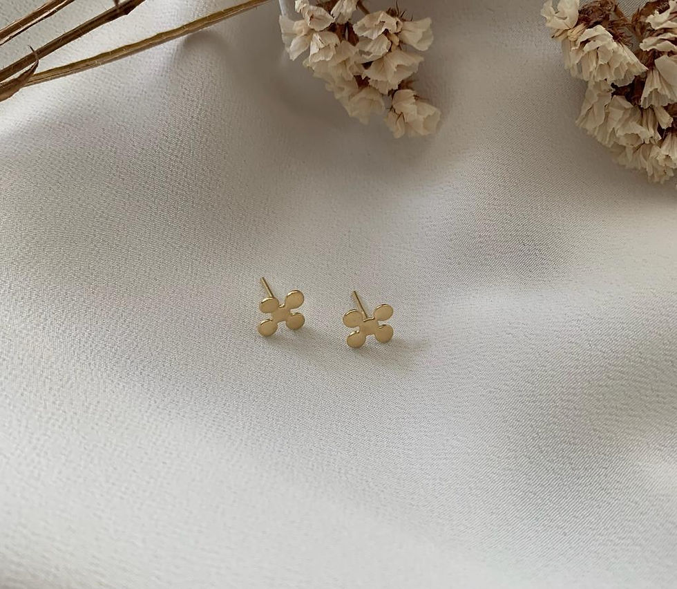 Brinco Apoio em ouro 18k, coleção Mãe de Ouro, cercado por flores brancas sobre tecido diáfano branco