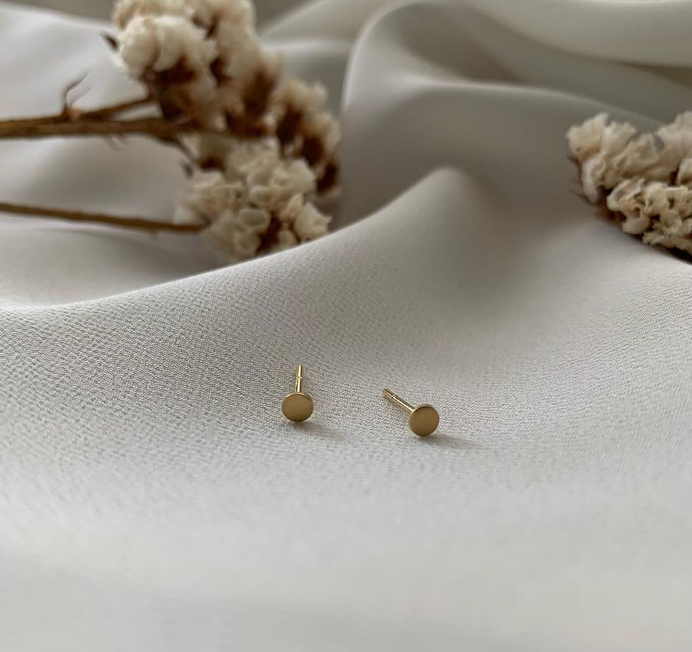 Brinco Célula em ouro 18k cercado por flores brancas sobre tecido diáfano branco