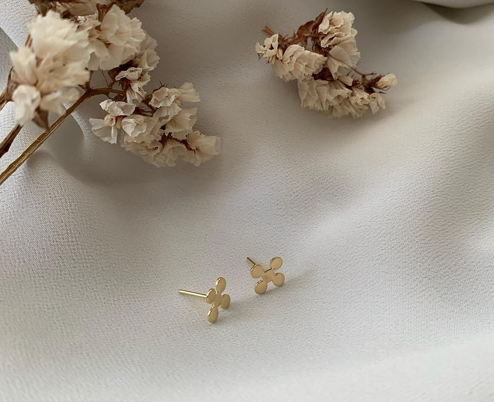 Brinco Apoio em ouro 18k, coleção Mãe de Ouro, cercado por flores brancas sobre tecido diáfano branco