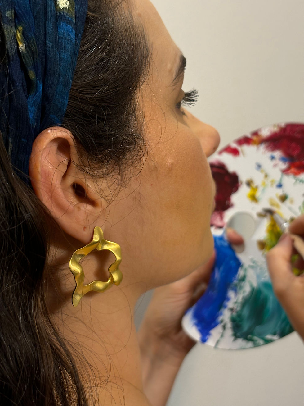 detalhe, Brinco Flor dourado usado por modelo segurando flores