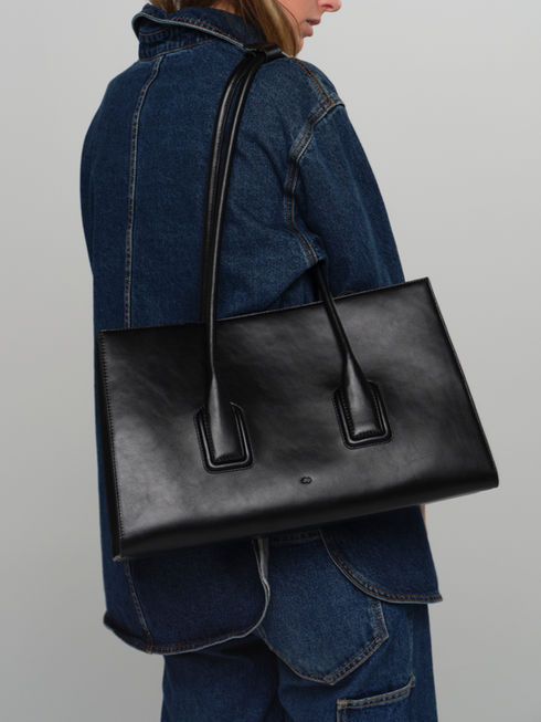 Model wearing the MATEO handcrafted leather tote bag in black.