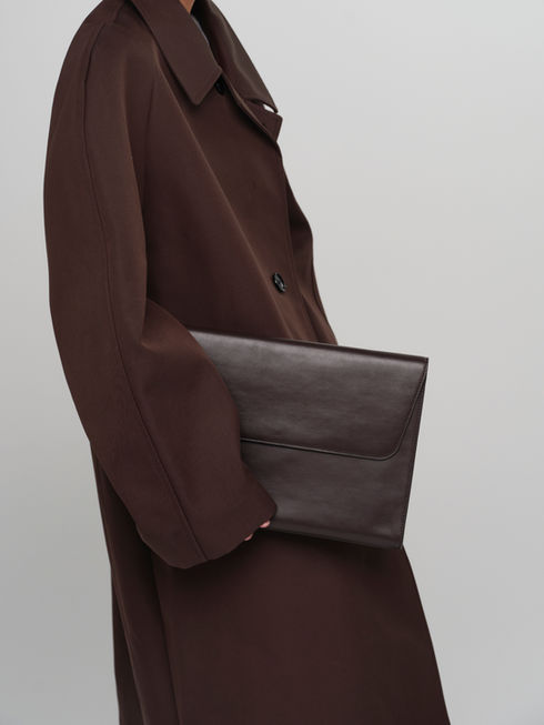 CLEO maxi envelope leather clutch in rich chocolate brown - on model for scale and size