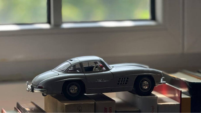 Miniatura de carro sobre mesa de livros ilustrando ideias de presentes criativos para homens