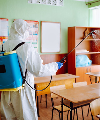 Back view professional sanitary worker disinfecting classroom before academic year starts