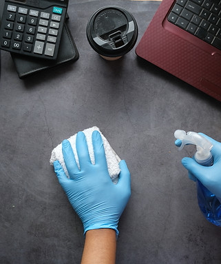 hand blue rubber gloves holding spray bottle cleaning office table