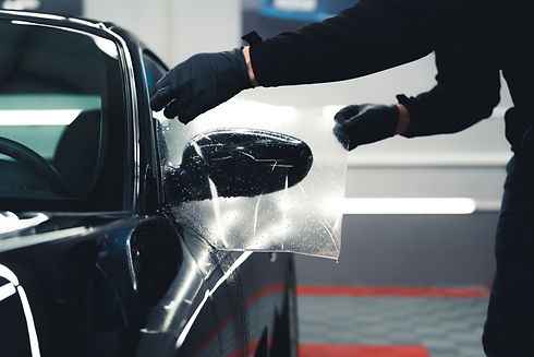 unrecognisable-man-wearing-black-gloves-leaning-stretching-ppf-paint-protection-film-side.